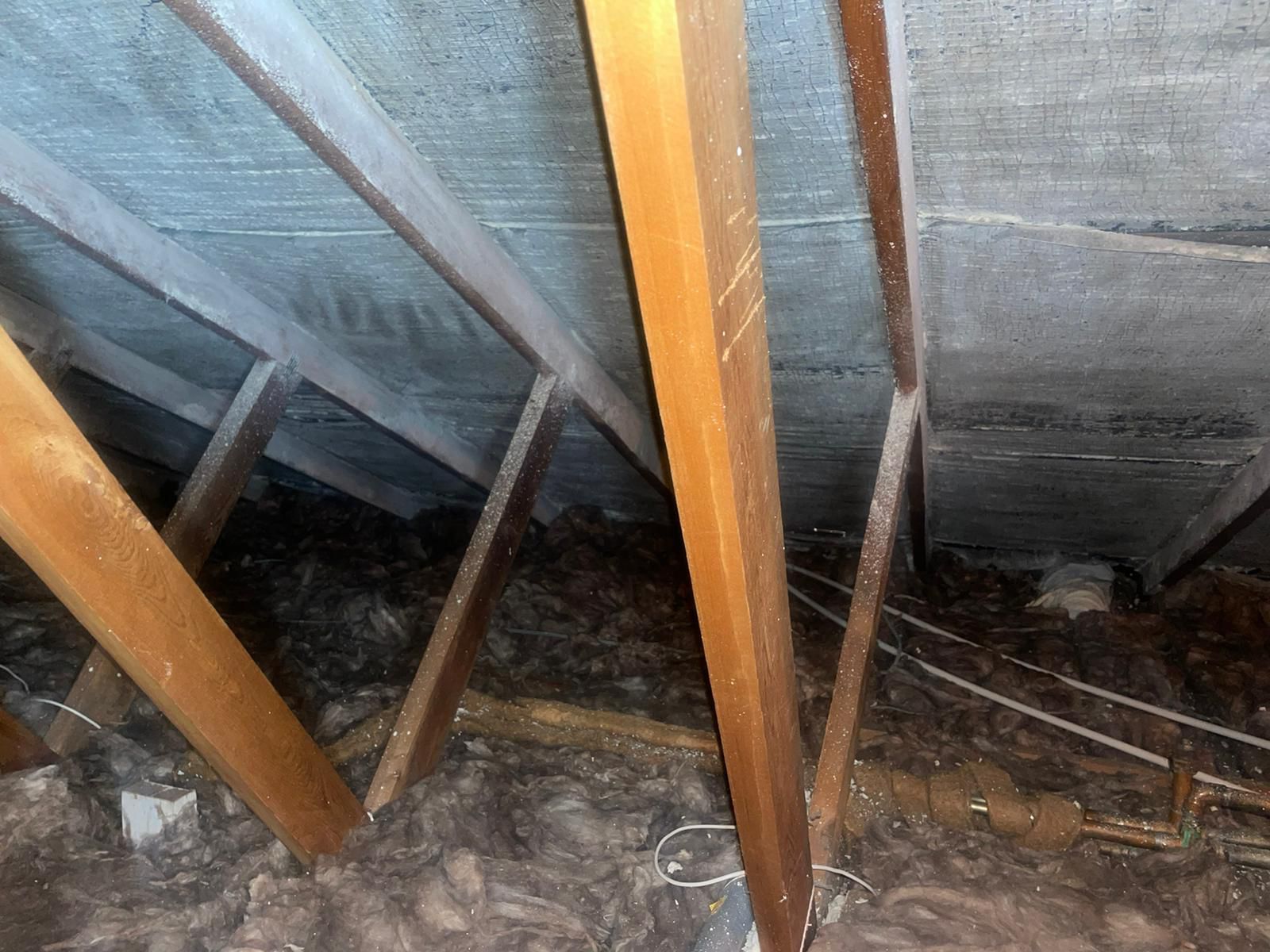 Multi-foil insulation lining a pitched roof behind its rafters, with mineral wool across the loft floor
